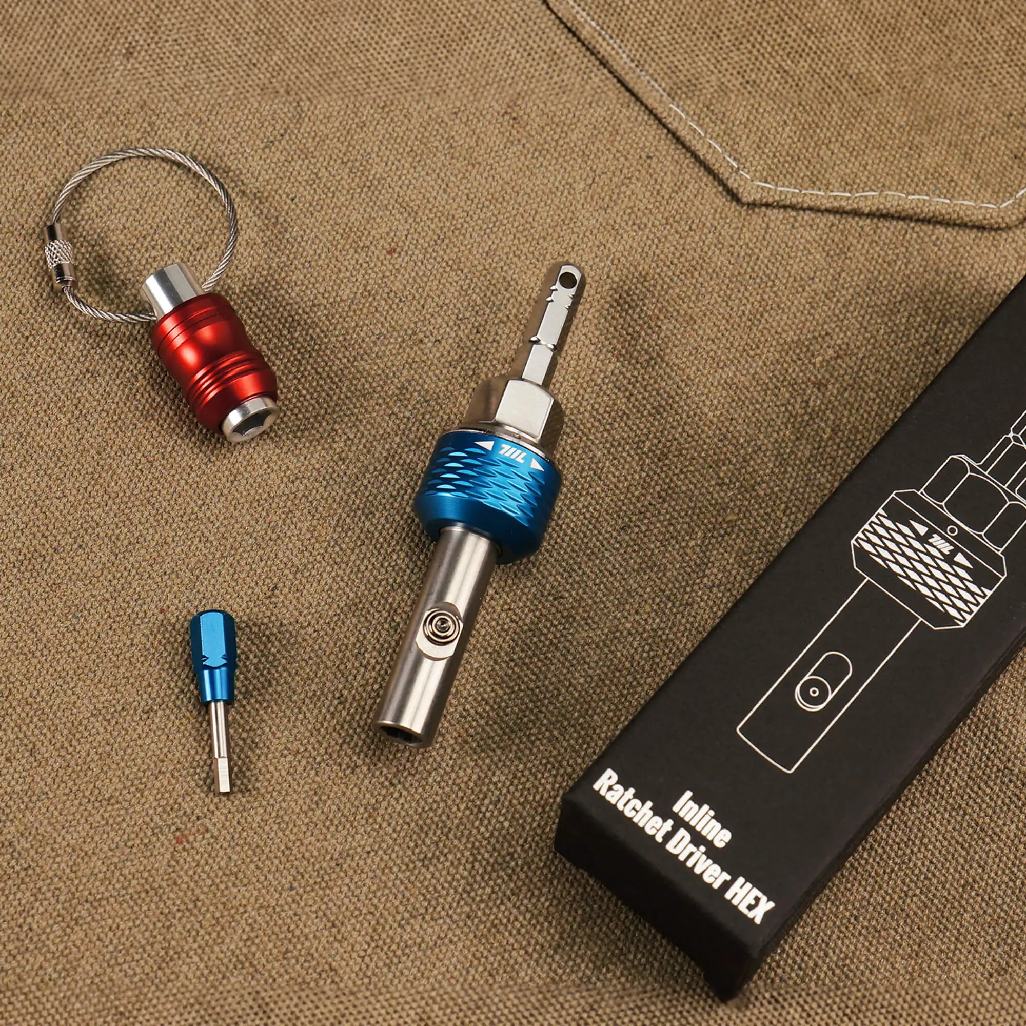 The 711L inline ratchet driver HEX displayed with a keychain adapter, spare bit, and packaging on a tan surface